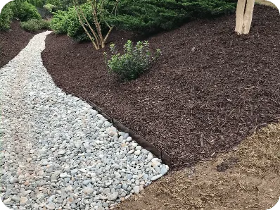 Finished river rock bed beside a mulched planting area