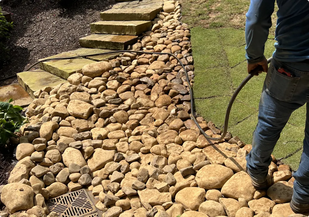 Crew installing a river rock drainage bed